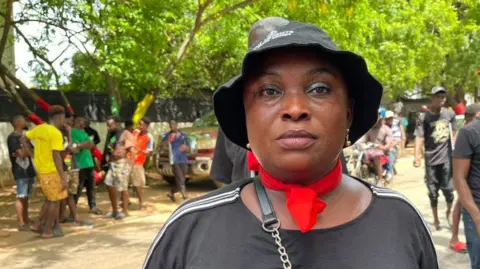 Serwaa Akoto, a protester wearing red and black clothing, speaks to the BBC.