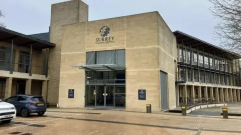 A large building with two parked cars.