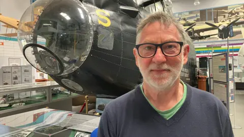 Photograph of the local war historian Frank Pleszak at the Avro Heritage Museum in Stockport. He's pictured in front of the cockpit of a Lancaster bomber.