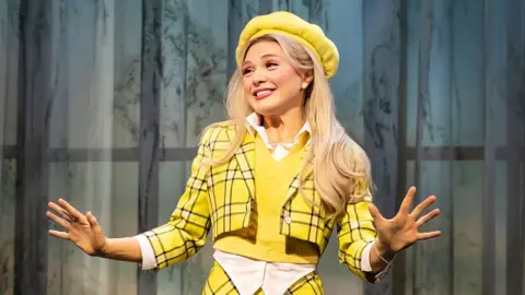 Pamela Raith Emma Flynn in bright yellow checked costume as Cher in Clueless The Musical