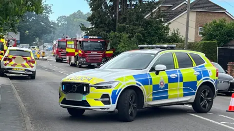 Julia Gregory/BBC A police car, along with two fire engines and a fire service command unit, parked on a street. 