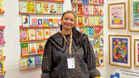 Daisey Burke Kerrie McNeill standing in tradeshow booth with colourful cards.