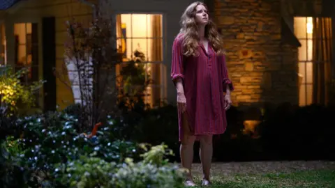 Projecteur Amy Adams dans Nightbitch, photographié debout dans le jardin, regardant le ciel