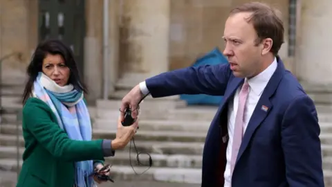 Reuters Matt Hancock hands a microphone to his aide Gina Coladangelo, following a television interview outside BBC"s Broadcasting House in London, Britain, May 16, 2021