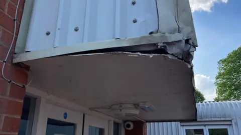 A large metal tear on the roof of a hospital building which lays in disrepair.