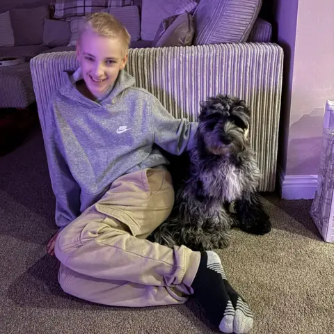 Stephanie Muirhead Andrew wearing a grey hoodie with a small white Nike motif on the upper right chest sitting next to a black and grey dog.