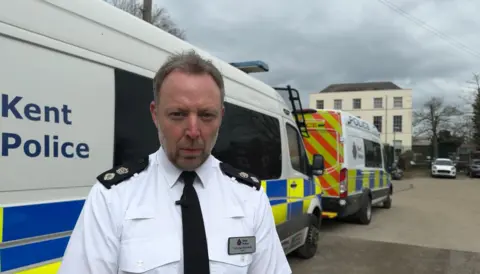 BBC/Jadzia Samuel Chief Superintendent Rob Marsh is standing outside two police vans at Kent Police headquarters in Maidstone