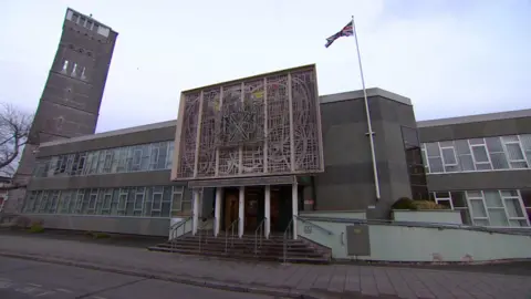 BBC An outside shot of Plymouth Crown Court. The sky is cloudy with patches of blue and white. 