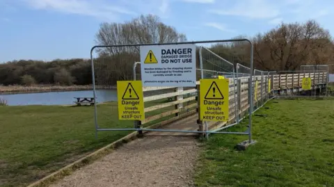 Melton Borough Council Bridge with gate at one end and danger signs with lake in background
