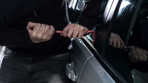 Getty Images File image of a man breaking into a car