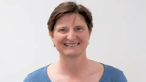 A woman with dark hair and a light blue jumper
