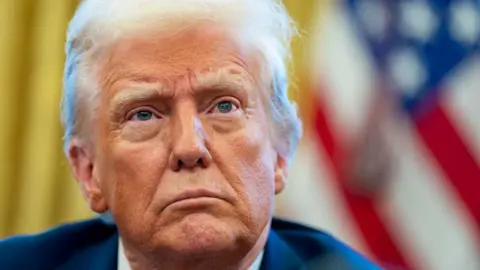 Getty Images Trump, looking and frowning in front of the yellow background