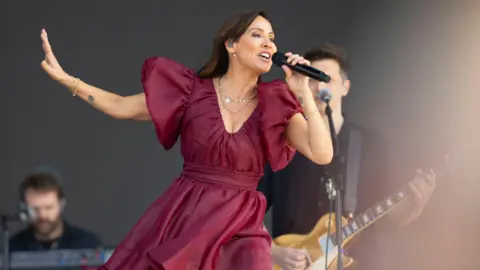 Natalie Imbruglia wearing a red dress singing on stage at Hyde Park in 2024