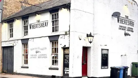 Dale Smith The exterior of the Wheatsheaf pub in Calne, Wiltshire, it is painted white with a large black door and the name of the pub written on the second floor.