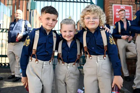 oung members of a flute band take part in the annual Twelfth of July parade. They are wearing dark blue shirts with khaki trousers and braces.
