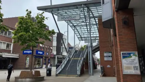 Exterior shot of the Harlquin Theatre in Redhill with a staircase leading up to the entrance covered by a glass canopy.