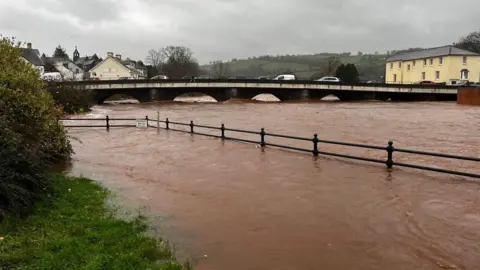 Watergate Miller | BBC Weather Watchers A river having burst its banks, with flood waters rising high against a bridge in the back ground. 