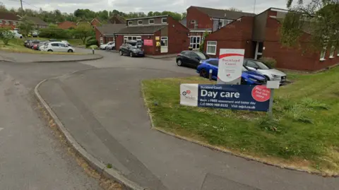 A Google maps image of a care home with small buildings and cars parked outside.