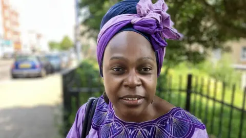 Councillor Amirah Cole, dressed in purple, looking at the camera