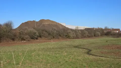 Supplied A winding path leads to piles of rubble and grey units at the site.