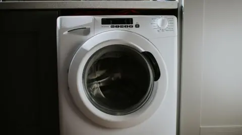 White front-load washing machine stowed under a table