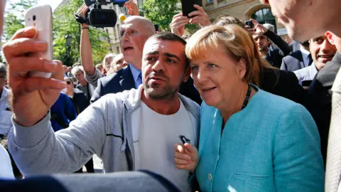 Angela Merkel takes a selfie with a Syrian refugee