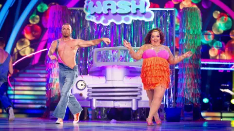 Robin Windsor and Lisa Riley jive in front of a car on the set of Strictly