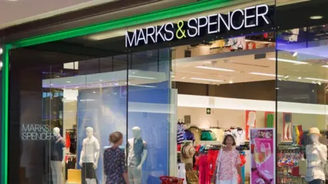 Two women walking in and out of a Marks and Spencer store
