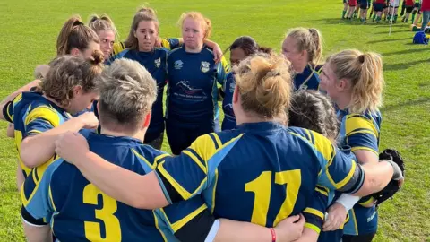 Trowbridge RFC A women's rugby team huddling togehter