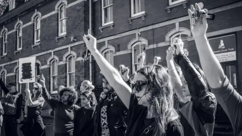 Courtenay Pipkin/This Ends Now A black and white image of a group of women protesting, holding up car keys to show how they defend themselves.