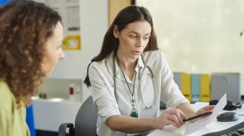 A stock image of a GP showing a patient a paper prescription.