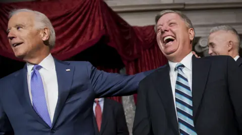 Getty Images Joe Biden puts his arm around a laughing Lindsey Graham in 2014