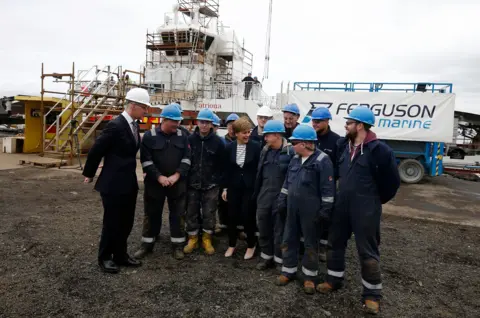PA Media Workers in blue helmets and blue overalls with Nicola Sturgeon and John Swinney
