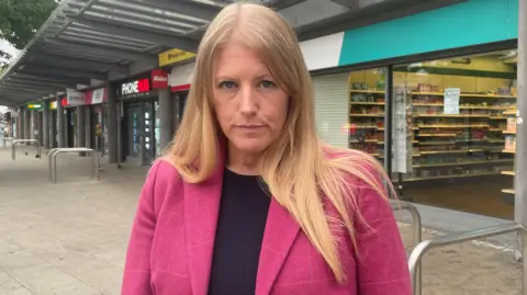 Donna jones wearing black and pink and stood in the high street