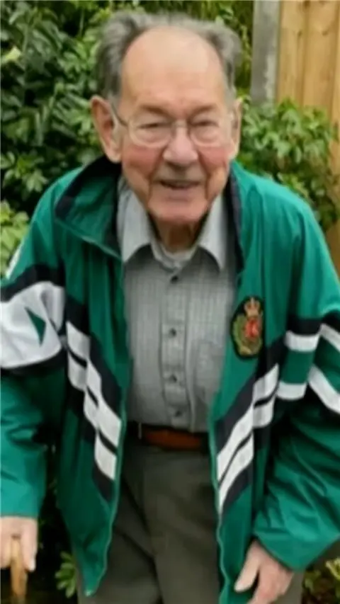 An elderly man in a green coat.