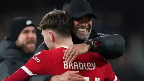 Liverpool manager Jurgen Klopp embraces Conor Bradley after the Carabao Cup semi final second leg match