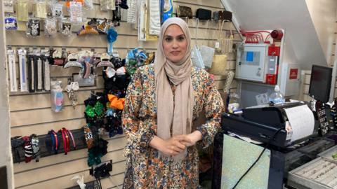 Nurum Ahmed standing by the till of her shop in Queensgate