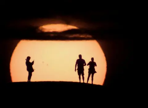 Borja Suarez / Reuters People silhouetted against the Sun