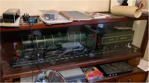 Green model locomotive in a wooden and glass case.