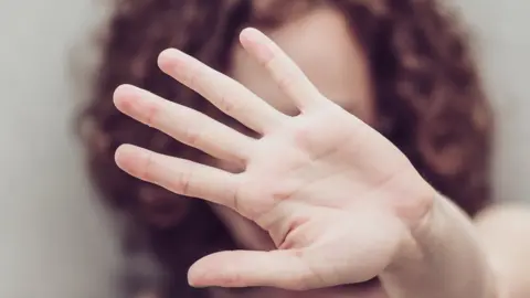 Getty Images File photo of a woman holding her hand up in a protective stance