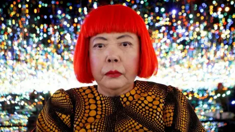 Japanese artist Yayoi Kusama poses for a photograph inside her Infinity Mirrored Room installation titled "The Souls of Millions of Light Years Away" during a media preview of her new exhibition at the David Zwirner gallery in New York, U.S.