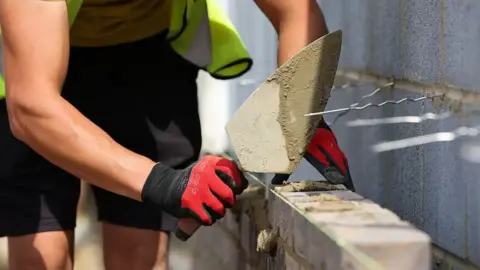 A generic picture of a bricklayer laying bricks.