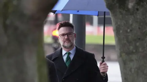 PA Media An image of Charles Hanson entering Derby Crown Court holding a blue umbrella 