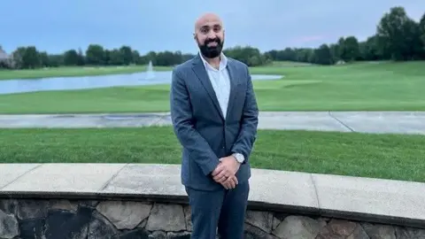 Ibrahim Awadallah Ibrahim Awadallah, a 30-year-old man, with a dark beard and moustache and wearing a suit, stands in front of a green lawn.