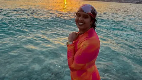 Rayfia Sherin A woman standing in the sea smiling.