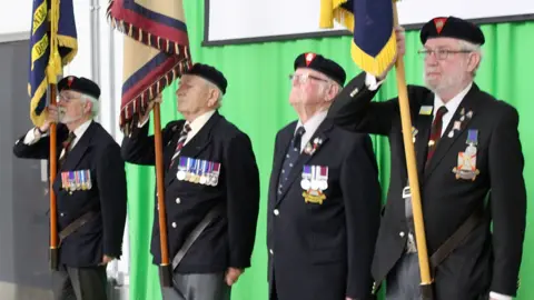 Melksham Oak Four members of the Royal British Legion carrying flags on stage 