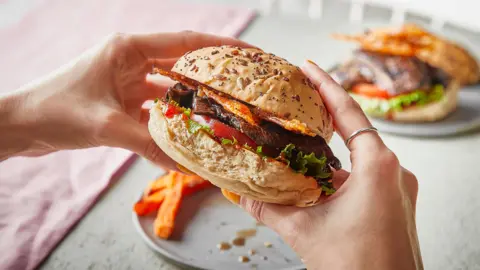 A pair of hands holds a mushroom burger in a bun. 