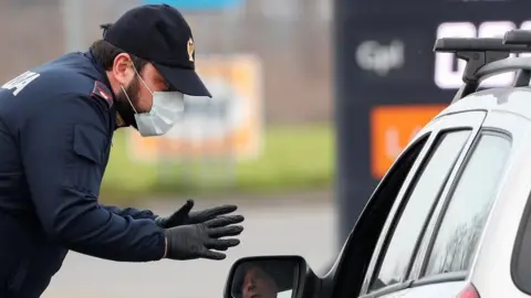 Reuters A policeman wearing a face mask warns a driver on the road between Codogno and Casalpusterlengo