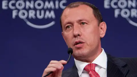 Getty Images Jahangir Hajiyev, who has a dark suit and red patterned tie, speaking into a microphone at the World Economic Forum.