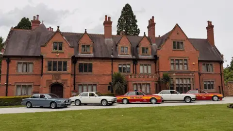 Five Jaguar XJ40s, including two in Fire Service livery, are parked outside Wappenbury Hall, a medieval manor house extended in the Victorian era, as part of Coventry Motofest.